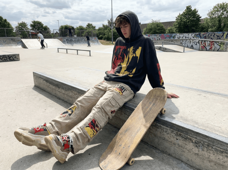 Streetwear outfit with oversized hoodie and cargo pants in a skate park.
